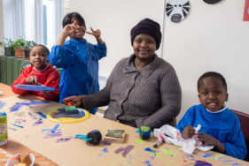 A mum and her three children are painting during a creative workshop.