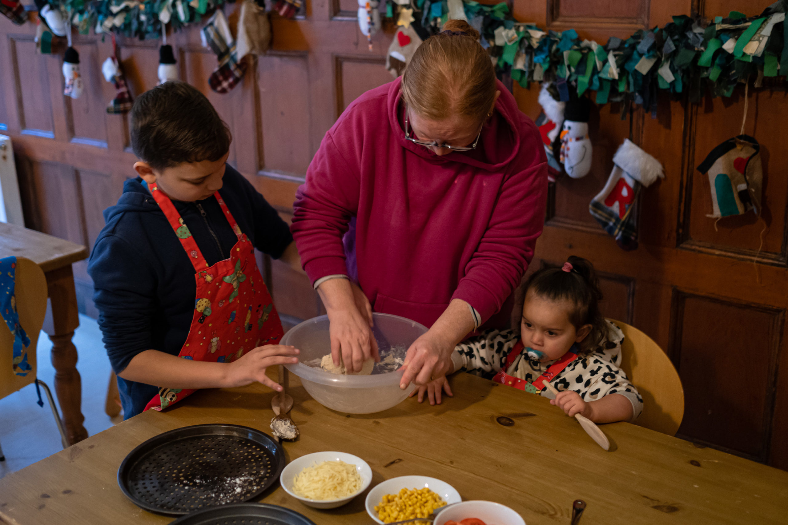 Tammy, a mother, is participating in a cooking activity with her two children. They are mixing flour into a bowl.